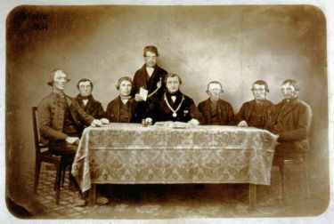 De gemeenteraad in 1865. Van links naar rechts L. Maas, G. Kesteloo, wethouder J. van der Weele, gemeentebode P. Joosse, burgemeester C.J. Baars, wethouder A. Boogert, P. van Vlaanderen en A. Filius.