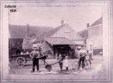 De oude smederij van de hoefsmid Van der Weele met ervoor de travalje voor het beslaan van de paarden en het gemeentelijk aanplakbord.