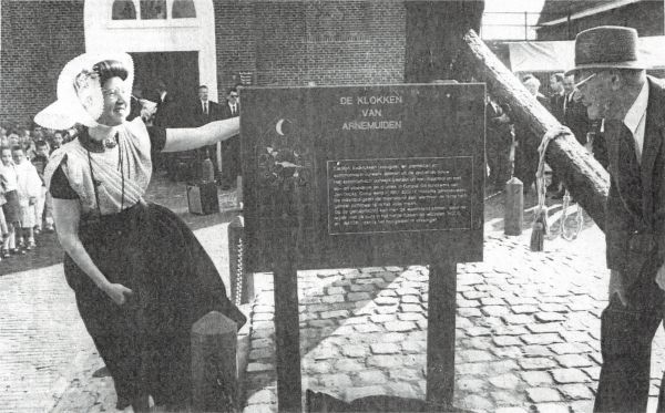 De echtgenote van burgemeester Visser en de heer Hoitsma bekijken het door hen onthulde informatiebord, waarop de geschiedenis en werking van de beroemde klok van Arnemuiden is beschreven.