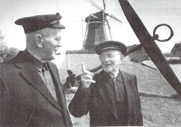 De nieuwe woningen op de plaats van de gesloopte mosselfabriek zijn gereed. Het eeuwenoude anker is opgesteld voor de nieuwe molen. De oude vissers Blaas Marijs (links) en Klaas Marijs (rechts) halen herinneringen aan vroeger op.