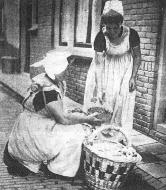 Volop bedrijvigheid met vis leuren. Grietje de Nooijer-van de Gruiter verkoopt een schaaltje garnalen bij een boerin op Walcheren.