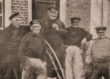 Oude vissers, rustend na een leven lang zwalken op zee in hun hoogaarzen. Links Joos van Belzen, de 88-jarige collectant voor de diaconie. Verder v.l.n.r nog een Joos van Belzen, Lieven van de Ketterij en Jozias de Rijke.